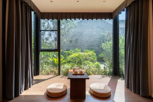 a room with large windows with a table and stools at 黄石未苏湾花间亭飞花 in Xialu