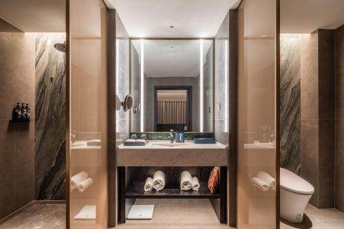 a bathroom with a sink and a toilet and a mirror at 黄石未苏湾花间亭飞花 in Xialu