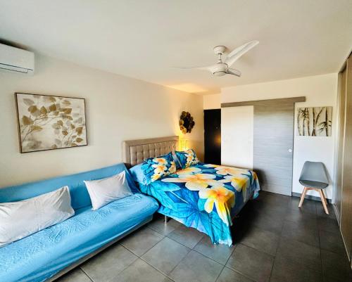 a bedroom with a blue couch and a bed at Tehautahi Cozy Lodge 2 in Papeete