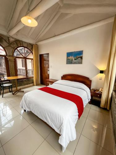 a bedroom with a large bed with a red blanket at Hotel Cusco Plaza Saphi in Cusco