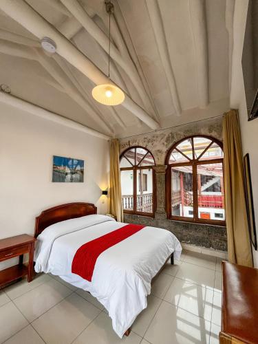 a bedroom with a large bed and windows at Hotel Cusco Plaza Saphi in Cusco