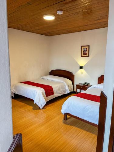 two beds in a room with wooden floors at Hotel Cusco Plaza Saphi in Cusco