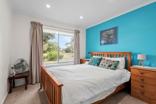een slaapkamer met blauwe muren en een bed met een raam bij The Abbey in Point Lonsdale