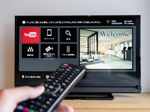 a person holding a remote control in front of a television at the square hotel KANAZAWA in Kanazawa