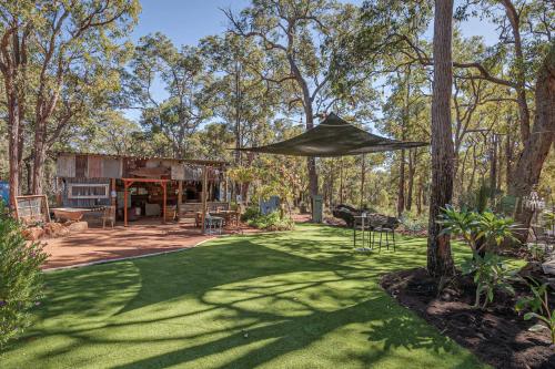 a yard with a house with a large umbrella at Jarrah Valley Escape by Tiny Away in Bedfordale