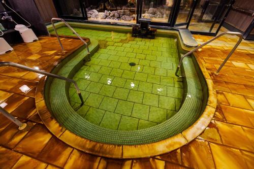 a circular pool in a room with a wooden floor at KAMENOI HOTEL Nara in Nara