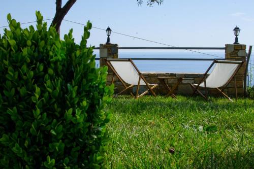 two chairs and a table in the grass at Guesthouse Enastron in Chorefto