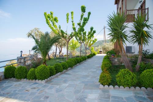 a walkway with bushes and trees next to a building at Guesthouse Enastron in Chorefto