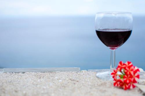 a glass of wine and a flower on the beach at Guesthouse Enastron in Chorefto