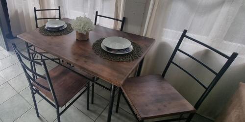a wooden table and chairs with plates and bowls on it at JDs Tropical stays in Cairns