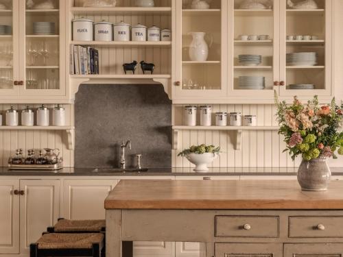 a kitchen with white cabinets and a table with a vase of flowers at Rosewood Cape Kidnappers in Te Awanga