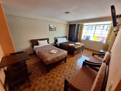 a hotel room with two beds and a table and chairs at Chaska valle Inn in Urubamba