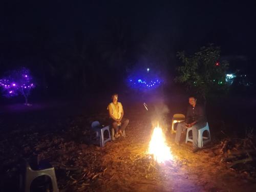 three people sitting around a fire at night at Healing Home And Hostel Auroville in Puducherry