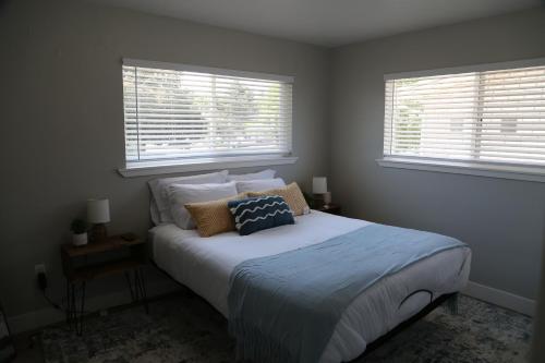 a bedroom with a bed with pillows and two windows at Updated 4-bedroom home centrally located in Logan