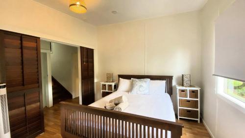 a bedroom with a bed with white sheets and a window at Surfside in Wooli