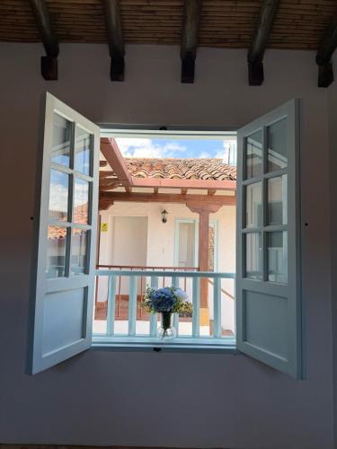 an open window with a vase of flowers on a balcony at Encanto Azul in Villa de Leyva
