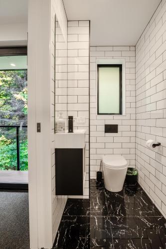 a white bathroom with a sink and a toilet at Family Size Holiday Home With Remarkable Views & Sauna, Close to Town in Queenstown