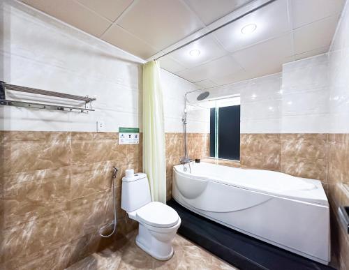a bathroom with a toilet and a tub and a sink at Quoc Cuong Center Da Nang Hotel by Haviland in Da Nang