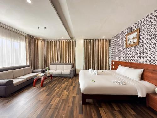 a hotel room with a large bed and a couch at Quoc Cuong Center Da Nang Hotel by Haviland in Da Nang