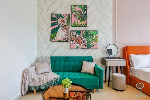a living room with a green couch and four paintings at Paxtonz Seasonal Suites in Petaling Jaya