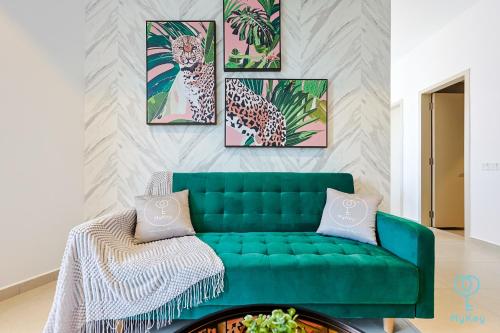 a living room with a green couch and four paintings at Paxtonz Seasonal Suites in Petaling Jaya