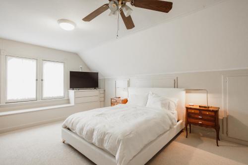 a white bedroom with a bed and a ceiling fan at Kaleidoscope Inn & Gardens in Nipomo