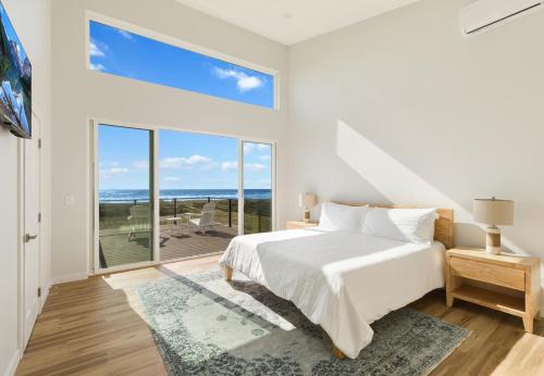 a white bedroom with a bed and a large window at The Beachcomber - Oceanfront Getaway! in Westport
