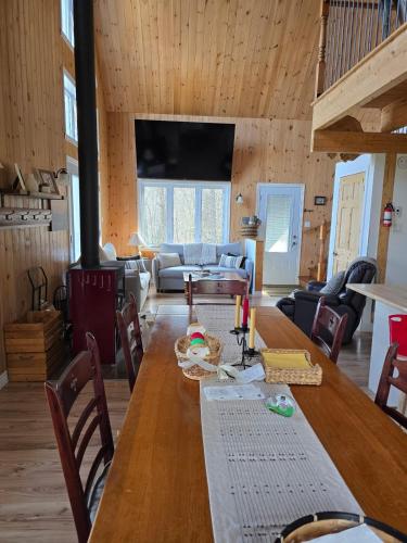 a dining room and living room with a wooden table at La Cabane du Couturier in Sainte-ThÃ¨cle