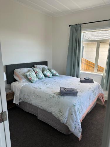 a bedroom with a bed with pillows and a window at Cottage on Matilda in Timaru