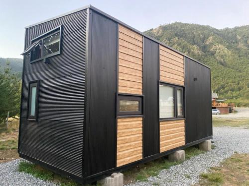 a black and wooden house sitting on a field at Malalcahuello Tiny House in Curacautín