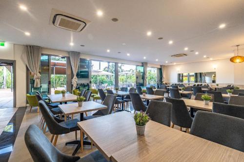 a restaurant with tables and chairs and windows at Vitina Studio Motel in Darwin