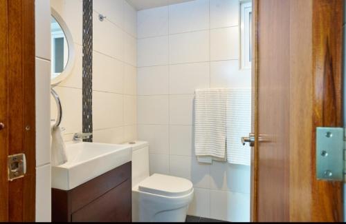 a white bathroom with a toilet and a sink at YOUR SPACE IN SANTO DOMINGO Gazcue in Colorado
