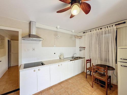 Il comprend une cuisine avec des placards blancs et un ventilateur de plafond. dans l'établissement Appartement cosy pour 2, proche plage aux Saintes-Maries-de-la-Mer - FR-1-475-184, à Saintes-Maries-de-la-Mer