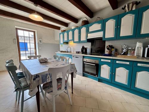 une cuisine avec des armoires bleues et une table et des chaises dans l'établissement Maison rénovée 6 couchages à Saint-Pierre-d'Oléron avec cour commune - FR-1-246A-349, à Saint-Pierre-dʼOléron