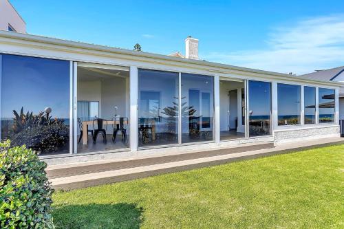 a house with large glass windows and a lawn at Norfolk on the Esplanade - Steps to Grange Beach in Grange