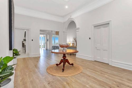 a living room with a table on a wooden floor at Norfolk on the Esplanade - Steps to Grange Beach in Grange