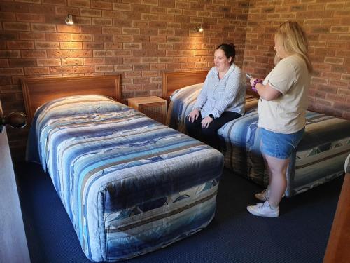 two women standing in a room with two beds at The Finley Palm Motor Inn in Finley