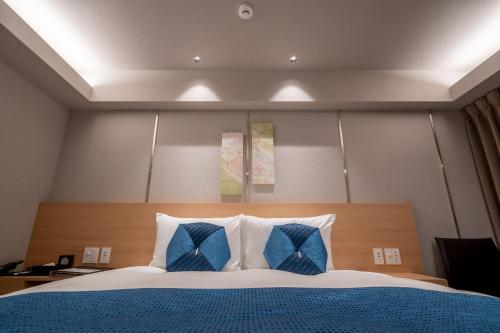 a bedroom with a bed with two blue pillows at RESI STAY Mayu Grace Hotel in Kyoto