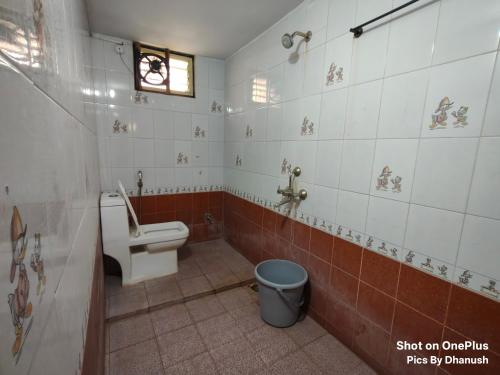 a bathroom with a toilet and a trash can at Annamaiah Guest House & Homestay - Tirupati - Home Food Service in Tirupati