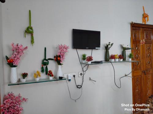 a room with a tv on a wall with vases at Annamaiah Guest House & Homestay - Tirupati - Home Food Service in Tirupati