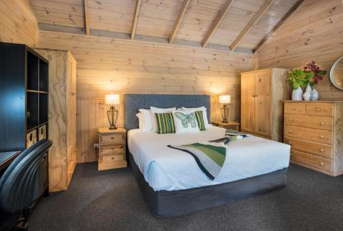 a bedroom with a large bed and wooden walls at Cosy Romantic Lodge, Perfect Couples Getaway in Sassafras