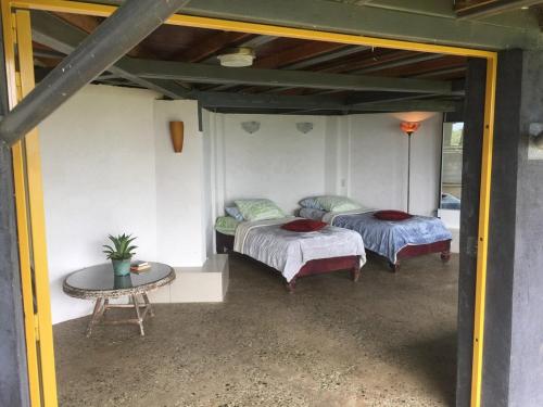 two beds in a room with a table and a table sidx sidx sidx at Hacienda las Nubes in Turrialba