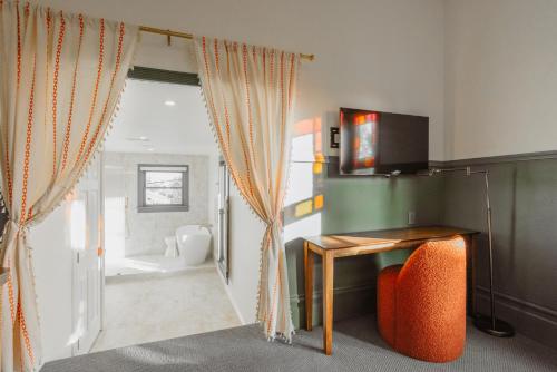 a room with a desk and a television and a bathroom at Kaleidoscope Inn & Gardens in Nipomo