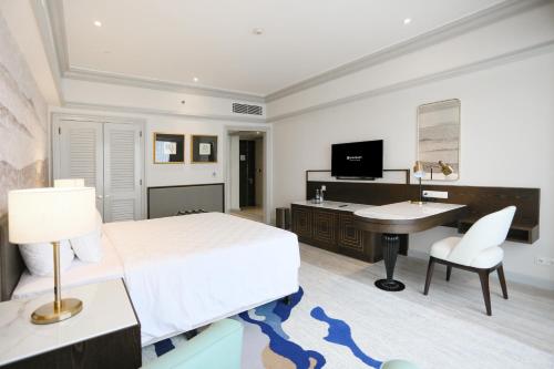 a bedroom with a bed and a desk and a sink at Wyndham Casablanca Jakarta in Jakarta