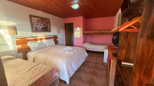 a bedroom with two beds in a room with pink walls at Pousada Pinhalense in Santo Antônio do Pinhal