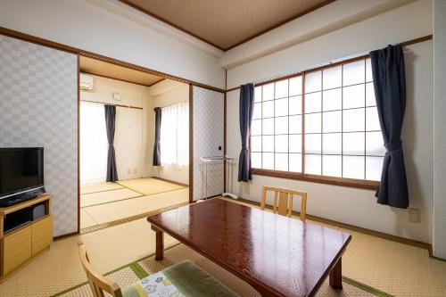 a living room with a wooden table and a television at ITO-SPA Guest House YAMATOSO in Ito