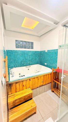 a bath tub in a bathroom with blue tiles at Pousada Pinhalense in Santo Antônio do Pinhal