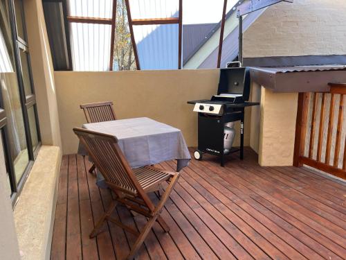 a patio with a table and a stove on a deck at Camdeboo Place in Dullstroom