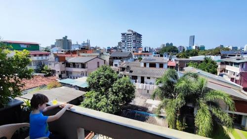 a boy standing on a balcony looking at a city at VIVAS Residencies Luxury Apartments in Colombo