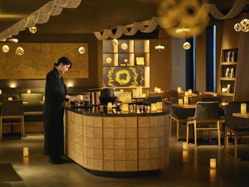 a man standing at a counter in a restaurant at OMO5 Kanazawa Katamachi by Hoshino Resorts in Kanazawa